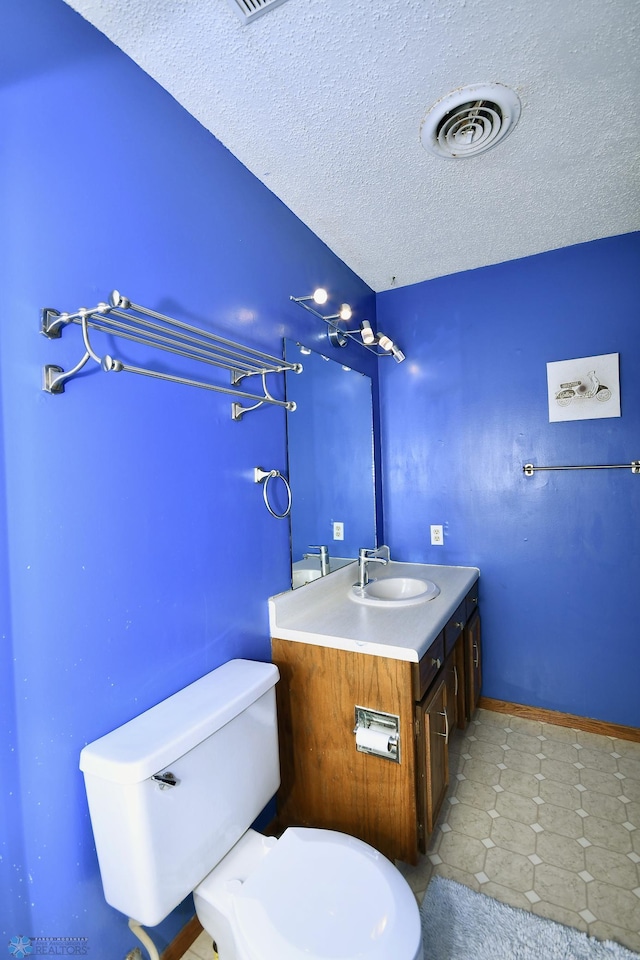 bathroom featuring tile patterned flooring, vanity, a textured ceiling, and toilet