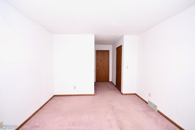 carpeted empty room with a textured ceiling