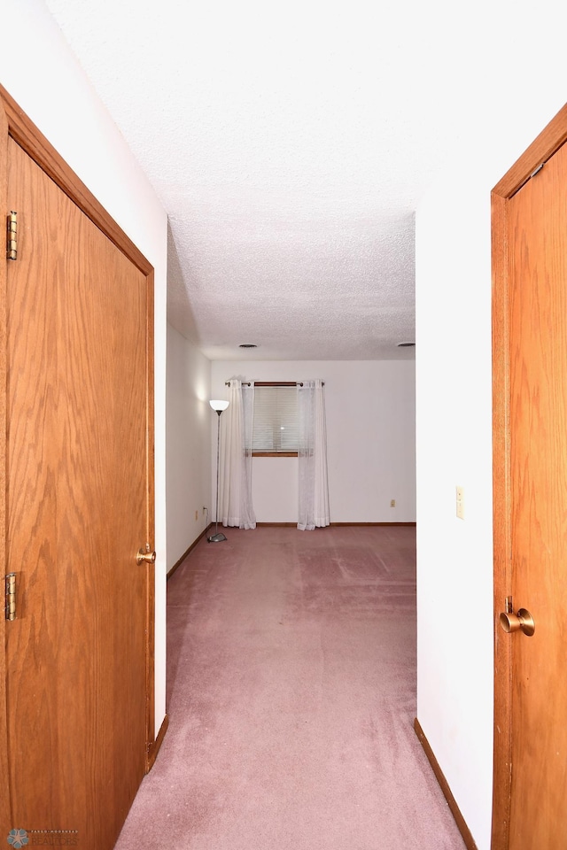 corridor with light carpet and a textured ceiling