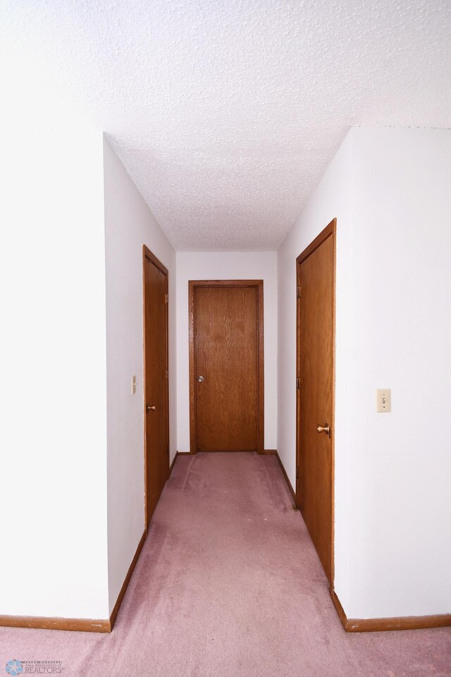 hall featuring a textured ceiling and light carpet