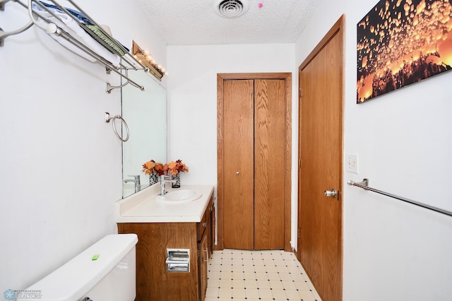 bathroom featuring vanity, toilet, and a textured ceiling