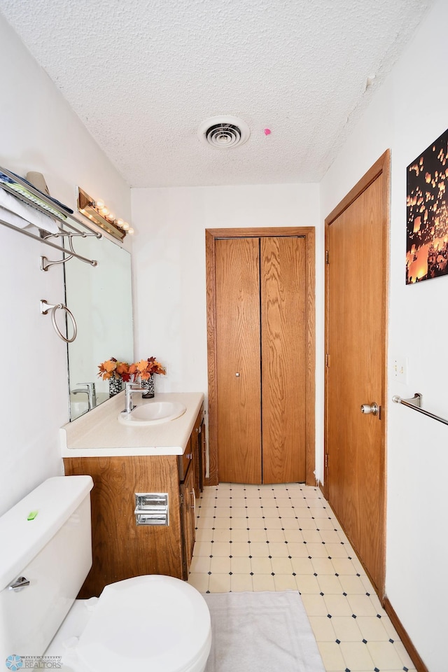 bathroom with vanity, a textured ceiling, and toilet