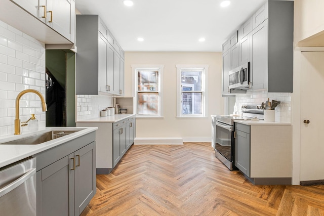 kitchen featuring gray cabinets, sink, light parquet flooring, and appliances with stainless steel finishes