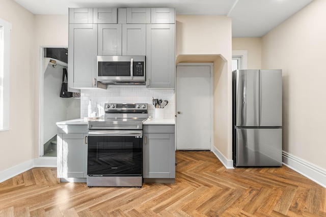 kitchen featuring stainless steel appliances, light parquet floors, and gray cabinetry