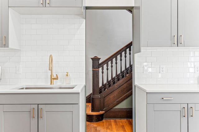 kitchen with backsplash, gray cabinetry, wood-type flooring, and sink