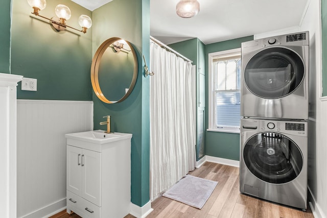 laundry area with sink, stacked washer and dryer, and light hardwood / wood-style flooring