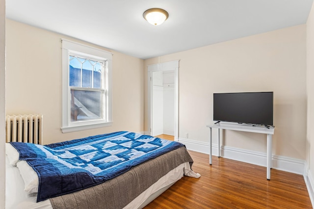 bedroom featuring radiator heating unit and wood-type flooring