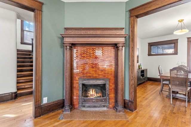 details with a warm lit fireplace, baseboards, and wood finished floors