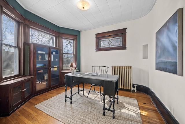 office with radiator heating unit, baseboards, and hardwood / wood-style floors