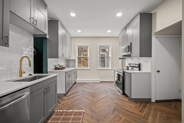 kitchen with stainless steel appliances, gray cabinets, light countertops, and a sink