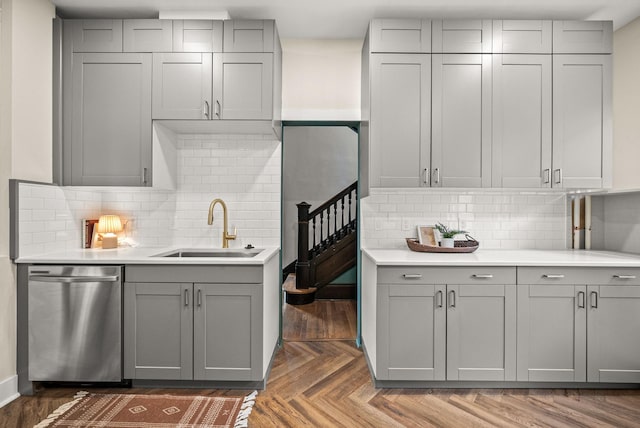 kitchen featuring stainless steel dishwasher, a sink, and gray cabinetry