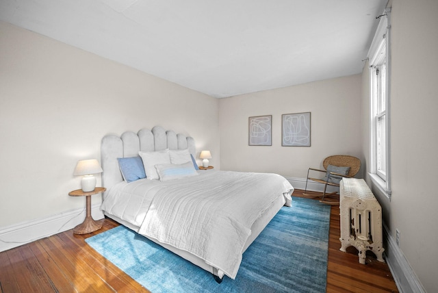 bedroom featuring radiator heating unit, wood-type flooring, and baseboards