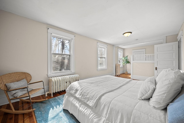 bedroom with baseboards, radiator heating unit, and wood finished floors