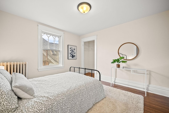 bedroom featuring baseboards, wood finished floors, and radiator