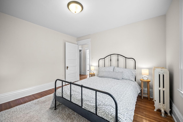 bedroom featuring baseboards, radiator heating unit, and wood finished floors