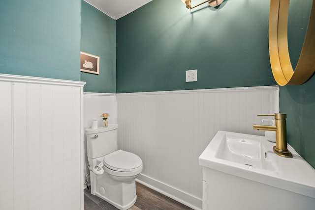 bathroom with vanity, wainscoting, wood finished floors, and toilet