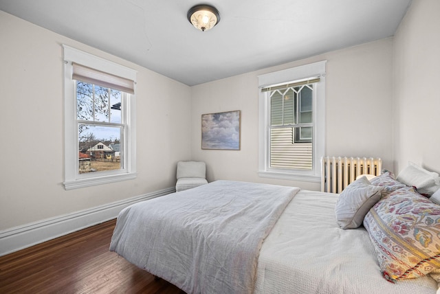 bedroom with radiator heating unit, wood finished floors, and baseboards