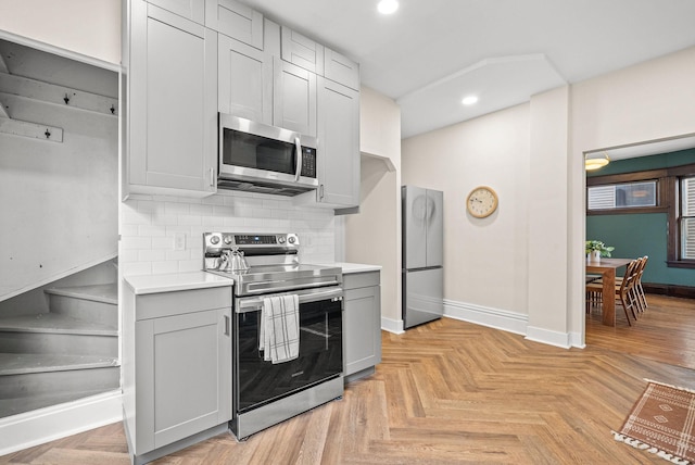 kitchen with stainless steel appliances, baseboards, light countertops, gray cabinets, and decorative backsplash