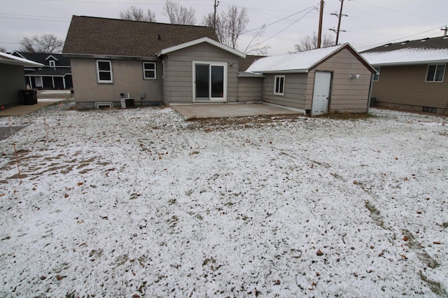 snow covered house featuring cooling unit and a patio