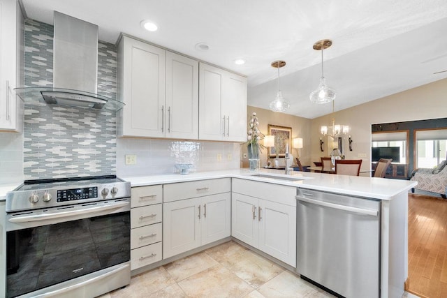 kitchen featuring sink, hanging light fixtures, stainless steel appliances, wall chimney range hood, and light hardwood / wood-style flooring