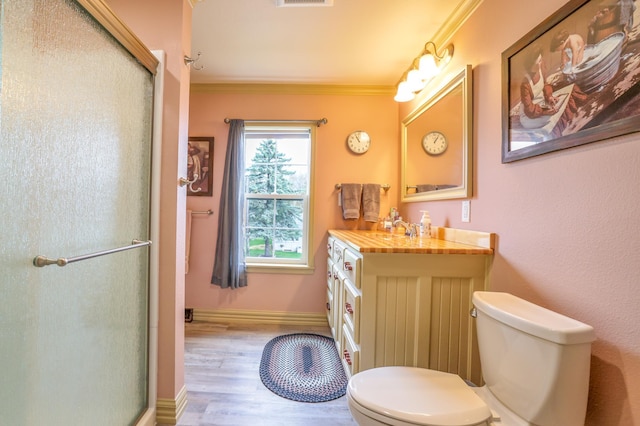 bathroom featuring wood-type flooring, toilet, walk in shower, and crown molding