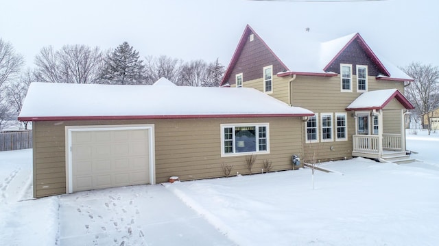 snow covered rear of property featuring a garage