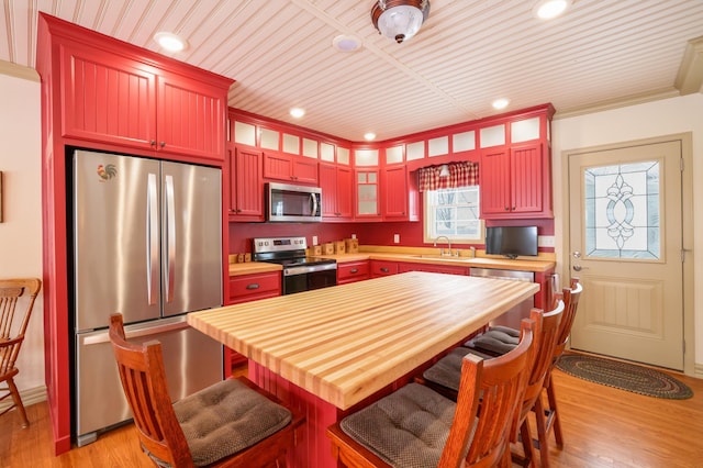 kitchen featuring glass insert cabinets, light wood finished floors, appliances with stainless steel finishes, and a sink