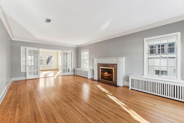 unfurnished living room with a fireplace, light hardwood / wood-style flooring, radiator, and ornamental molding