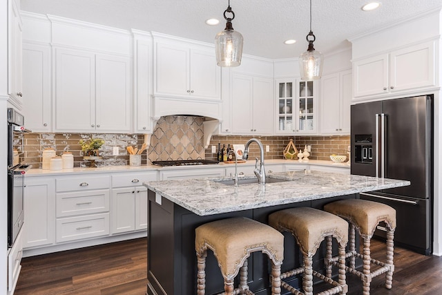 kitchen featuring dark hardwood / wood-style flooring, a textured ceiling, stainless steel appliances, sink, and a center island with sink