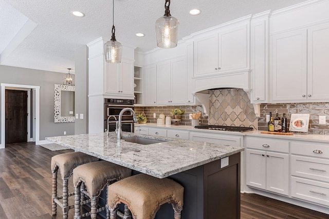 kitchen featuring dark hardwood / wood-style floors, a textured ceiling, and a kitchen island with sink