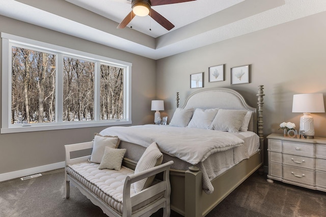 carpeted bedroom featuring a tray ceiling and ceiling fan