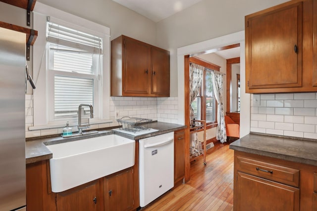 2724 Longfellow Ave, Minneapolis, MN 55407 - kitchen with white dishwasher, a sink, light wood-style flooring, and dark countertops
