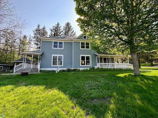 back of property with covered porch and a yard