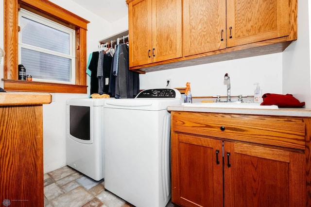 clothes washing area with washer and clothes dryer, cabinets, and sink