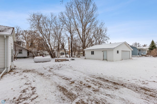 snowy yard featuring a garage and an outdoor structure