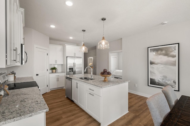 kitchen featuring white cabinetry, sink, stainless steel appliances, a center island with sink, and hardwood / wood-style flooring