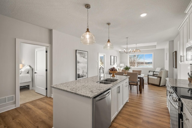 kitchen featuring sink, light hardwood / wood-style flooring, a center island with sink, white cabinets, and appliances with stainless steel finishes