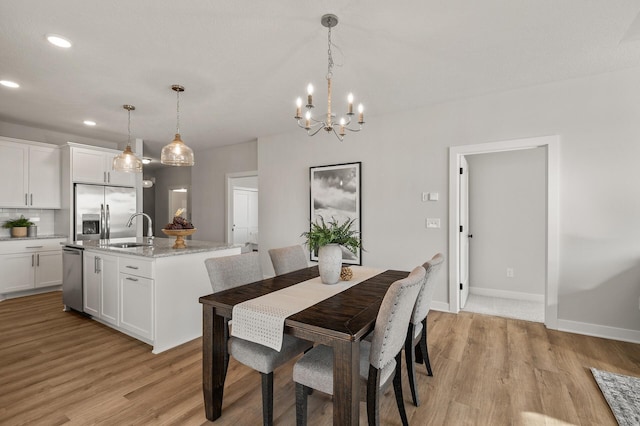 dining area featuring a chandelier, light wood-type flooring, and sink