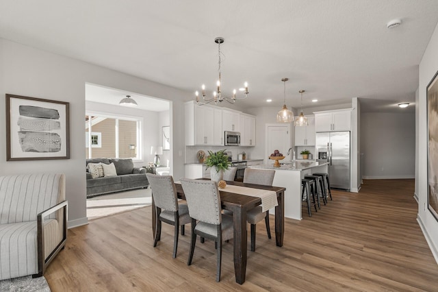 dining area with light hardwood / wood-style flooring, a chandelier, and sink