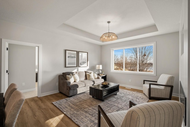 living room featuring hardwood / wood-style floors, a notable chandelier, and a tray ceiling