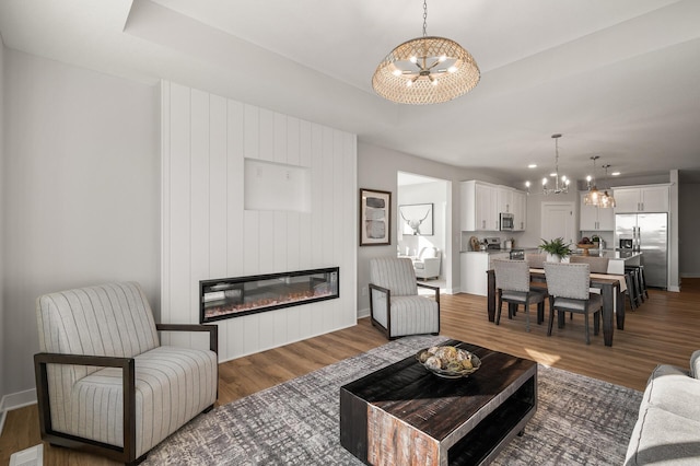 living room featuring a fireplace, dark hardwood / wood-style flooring, and an inviting chandelier