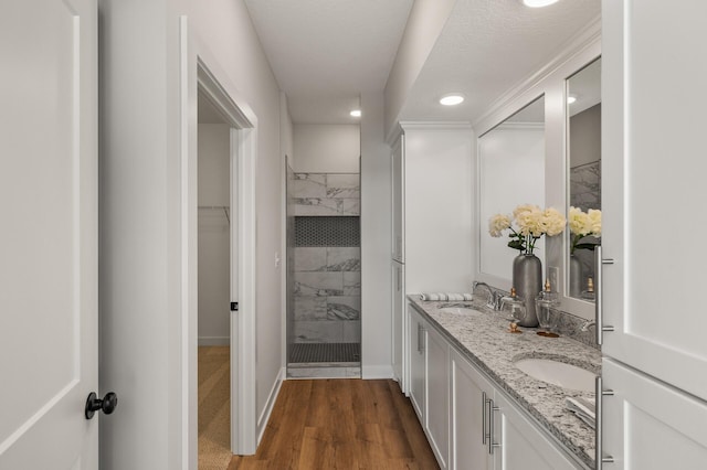 bathroom with a tile shower, vanity, a textured ceiling, and hardwood / wood-style flooring