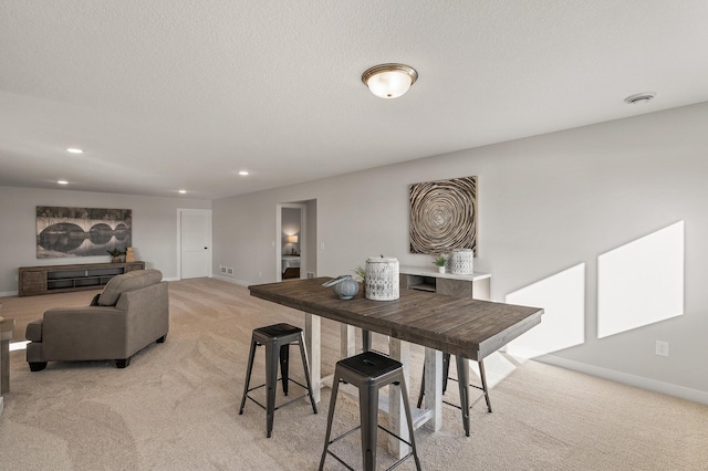 dining area featuring light colored carpet and a textured ceiling