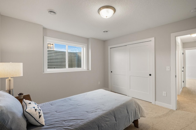 bedroom with light carpet, a textured ceiling, and a closet