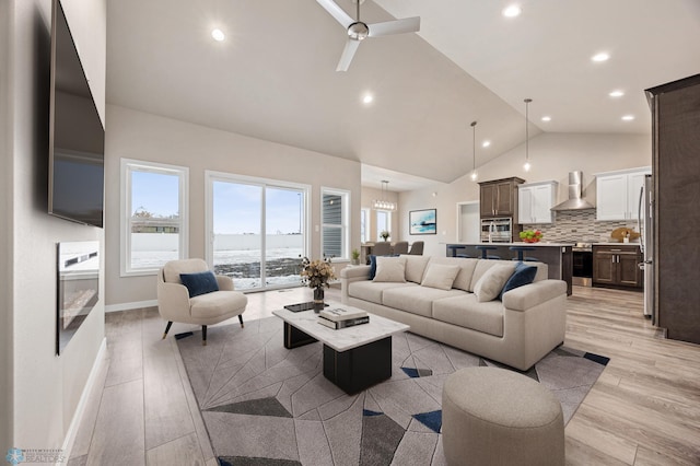 living room featuring ceiling fan, lofted ceiling, and light wood-type flooring