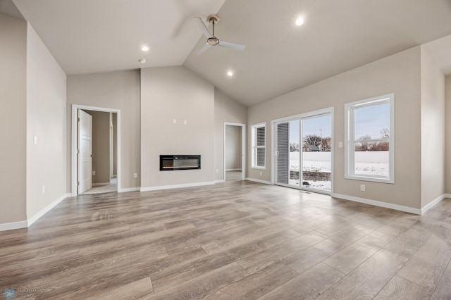 unfurnished living room featuring ceiling fan, light wood-type flooring, high vaulted ceiling, and heating unit