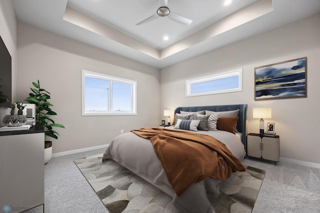 bedroom featuring ceiling fan, light colored carpet, and a tray ceiling