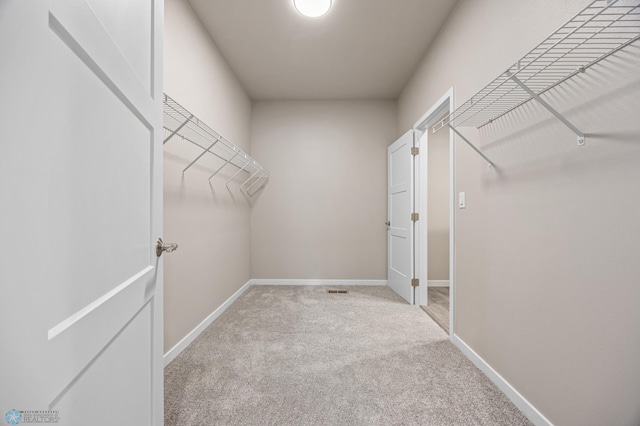 walk in closet with light carpet