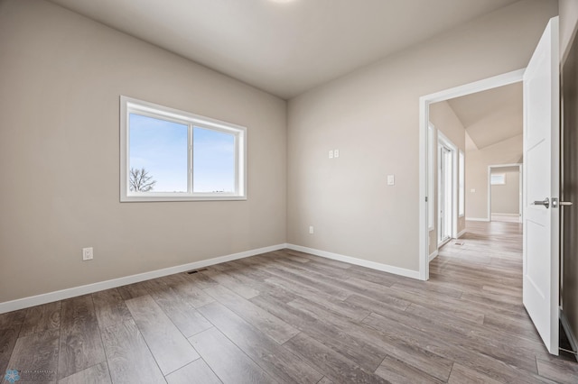 empty room with light hardwood / wood-style floors and lofted ceiling