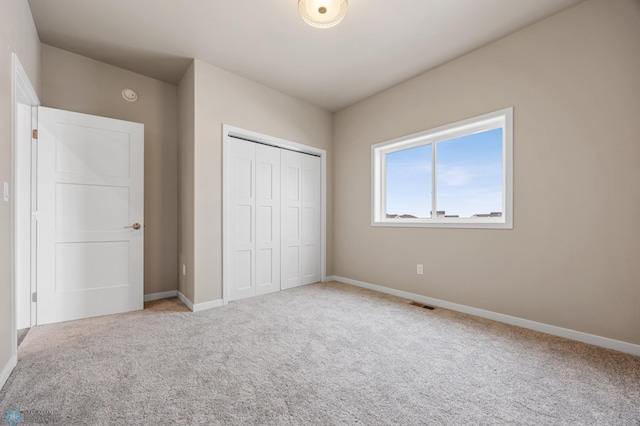 unfurnished bedroom featuring light colored carpet and a closet